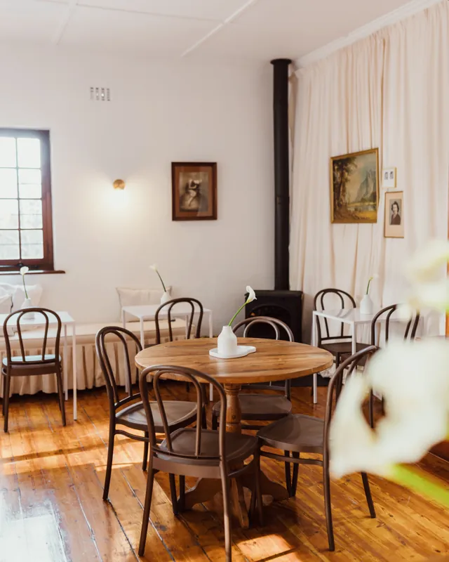 The front room: bentwood chairs around round wooden tables, old paintings on white walls.